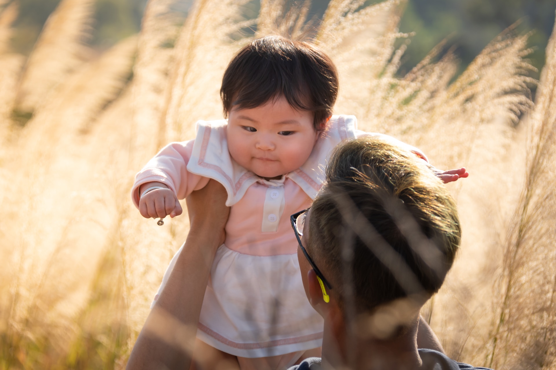 Asian daughter being lifted up in the air by father.